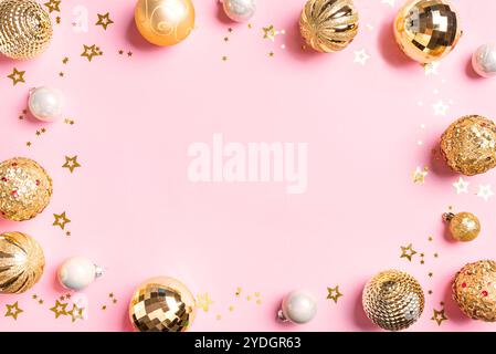 Christmas frame template: shine golden baubles on pink pastel background,  top view, copy space. Trendy Christmas festive design concept with golden o Stock Photo