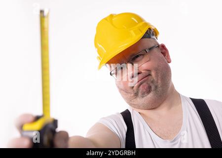A construction worker is expertly measuring dimensions using a tape measure on site Stock Photo