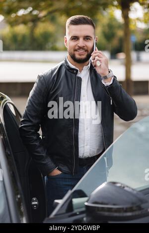 Young bearded man stand by his luxury car and speak by phone. Portrait of stylish man Stock Photo