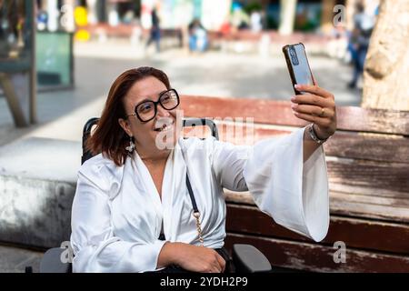 Woman in Wheelchair Smiling While Taking a Selfie Stock Photo