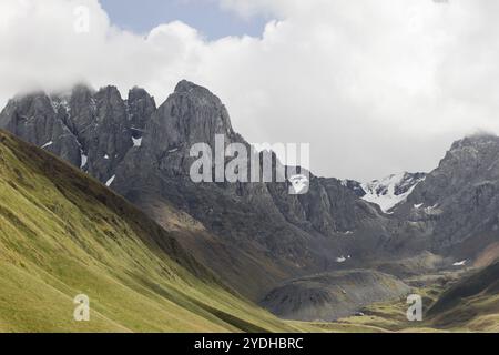 a striking view of a towering mountain range, where steep, rugged peaks dominate the landscape. The cliffs are sharp and jagged Stock Photo