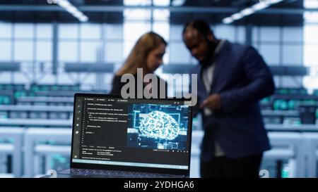 Close up of laptop with AI technology used to sustain data center hardware. Focus on notebook used by server room programmers in background using artificial intelligence tech, camera A Stock Photo