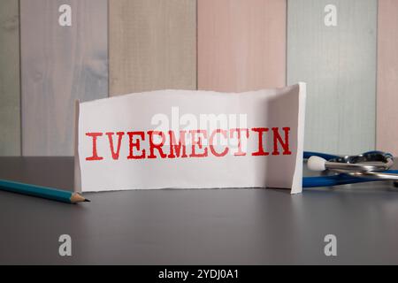 Doctor holding a card with text TREATMENT IS IVERMECTIN, medical concept. The text is written in blue letters in a medical journal. Stock Photo