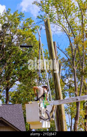 Lineman operates from raised lift to inspect maintain power transformer on a pole after hurricane Stock Photo