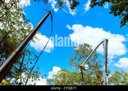 An electrical pole is repaired by technician using bucket lift following hurricane Stock Photo