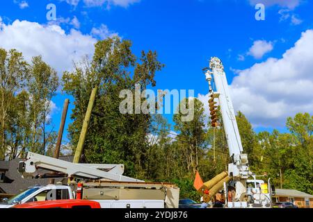 Utility maintenance is progress with technician on lift power lines transformer. Stock Photo