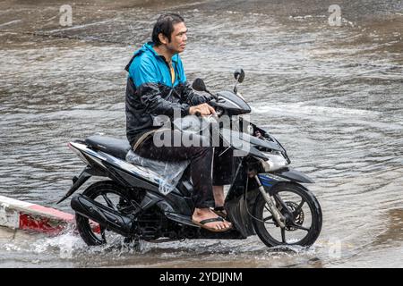 SAMUT PRAKAN, THAILAND, OCT 03 2024, A man rides a motorcycle on the street in the rain Stock Photo