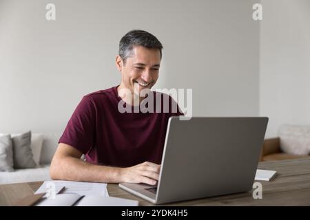 Happy Hispanic freelance entrepreneur man in casual working at laptop, Stock Photo