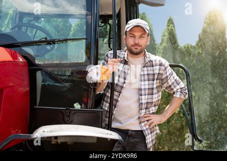 Caucasian man farmer stands next to agricultural tractor. Stock Photo