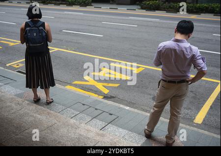 14.12.2018, Singapore, Republic of Singapore, Asia, Two people wait for their taxi on a roadside in Singapore's business district after work, Asia Stock Photo