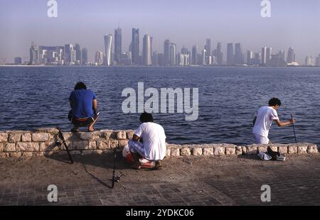 13.09.2010, Doha, Qatar Qatar, men fishing on the waterfront along Al Corniche Street with a view of the skyline of the Al Dafna business district in Stock Photo