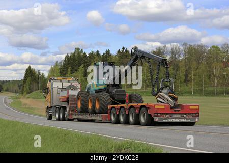 SALO, FINLAND, MAY 25, 2017: Yellow Volvo FH of Kosken Autokeskus transports Logman 811H forest harvester on gooseneck trailer along highway on a beau Stock Photo