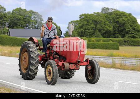 Kimito, Finland. July 6, 2019. Young man greets as he drives classic Porsche-Diesel Super Tractor on Kimito Tractorkavalkad, vintage tractor parade Stock Photo