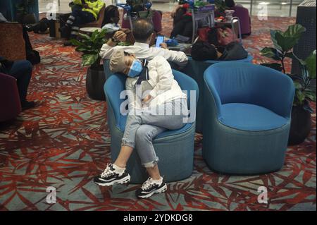 18.03.2020, Singapore, Republic of Singapore, Asia, A woman sleeps in an armchair in the arrivals area of Terminal 1 at Changi Airport. She is wearing Stock Photo