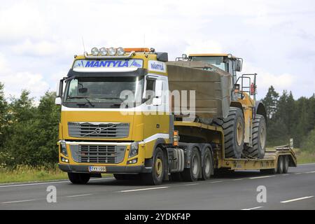 SALO, FINLAND, JULY 30, 2016: Yellow Volvo FH semi of Mantyla transports Caterpillar 980H wheel loader on drop deck trailer on rural highway at summer Stock Photo