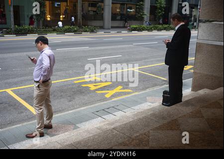 14.12.2018, Singapore, Republic of Singapore, Asia, Two men wait for their taxi on a roadside in Singapore's business district after work, Asia Stock Photo