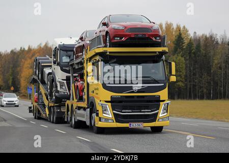 KAARINA, FINLAND, OCTOBER 14, 2016: Yellow Volvo FM car transporter hauls new cars along highway in autumn Stock Photo