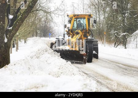 Yellow motor grader Vammas removing snow from street after heavy snowfall in Salo, Finland. January 22, 2021 Stock Photo