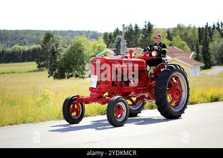 Kimito, Finland. July 6, 2019. Man drives red International Harvester Farmall M tractor, year 1951, on Kimito Tractorkavalkad, vintage tractor parade. Stock Photo