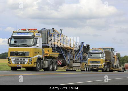 SALO, FINLAND, JULY 30, 2016: Two Yellow Volvo FH16 semi trucks of Mantyla E & E in heavy equipment haul stop for a moment by road in South of Finland Stock Photo