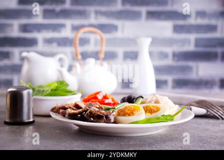 fresh breakfast, boiled eggs with rice meat and vegetables on plate Stock Photo