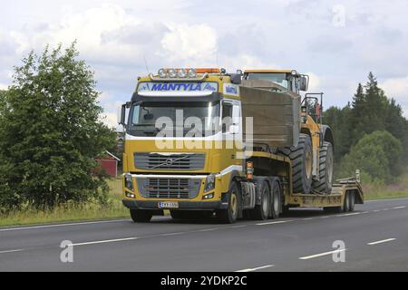 SALO, FINLAND, JULY 30, 2016: Yellow Volvo FH semi of Mantyla E&E transports Caterpillar 980H wheel loader on drop deck trailer on rural highway at su Stock Photo