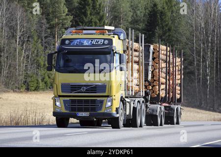 SALO, FINLAND, APRIL 21, 2017: Yellow Volvo FH16 logging truck transports a load of pine logs along highway at spring Stock Photo