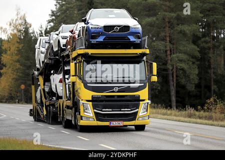 Yellow Volvo FM car transporter hauls new Volvo cars along rural highway in autumn. Salo, Finland. October 11, 2019 Stock Photo