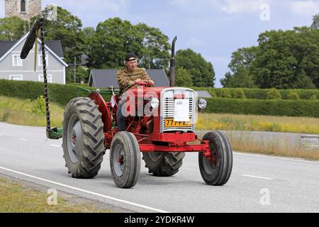 Kimito, Finland. July 6, 2019. Man drives Valmet 361 D tractor, year 1962, in front of farm equipment on Kimito Tractorkavalkad, vintage tractor parad Stock Photo