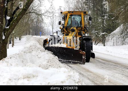 Yellow motor grader Vammas removing snow from street after heavy snowfall in Salo, Finland. January 22, 2021 Stock Photo