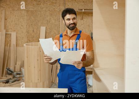 Worker carpenter looking at paper sheet with project blueprint at woodshop Stock Photo