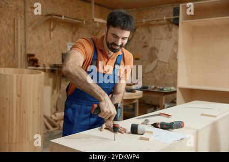 Carpenter working with drill making holes in plank Stock Photo