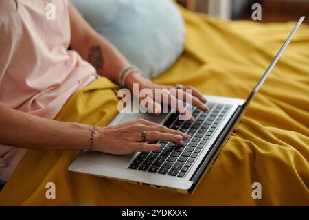 Typing on Laptop While Sitting on Yellow Blanket Stock Photo