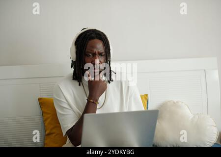 Pensive Man Wearing Headphones Using Laptop Stock Photo