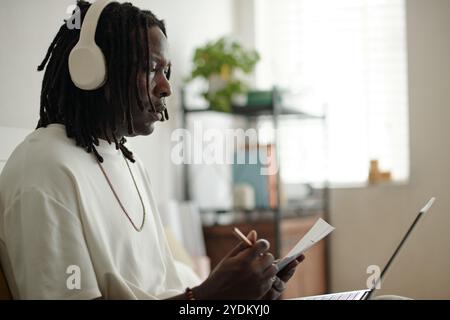 Young Man Listening to Music While Writing Notes Stock Photo