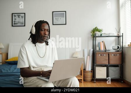 Portrait of African American Man Using Laptop in Bedroom Stock Photo