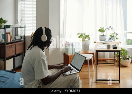 Young Man Wearing Headphones While Working on Laptop Stock Photo
