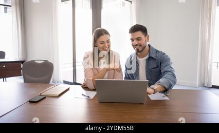 Couple of happy business workers talking at laptop Stock Photo