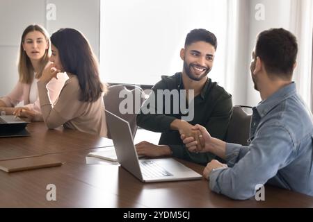 Cheerful young Arabic business professional shaking hands with partner Stock Photo