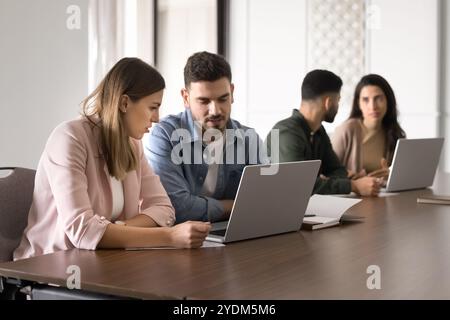Couple of serious business colleagues sharing laptop for teamwork Stock Photo