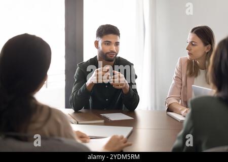 Serious young Middle Eastern project manager talking to partners Stock Photo