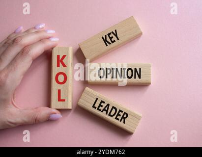 KOL - Key Opinion Leader symbol. Concept word KOL on wooden blocks. Businessman hand. Beautiful pink background. Business and KOL concept. Copy space. Stock Photo