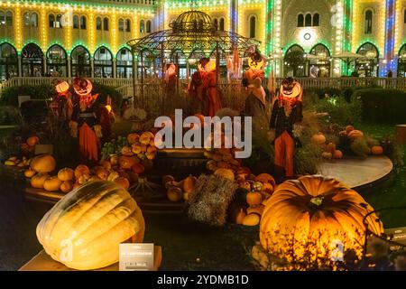 Halloween display at Tivoli Gardens, featuring illuminated jack-o'-lantern-headed figures and a vibrant array of pumpkins, against colorful lights Stock Photo