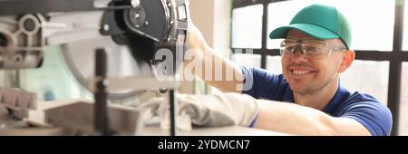 Smiling employee cuts wooden board with sawing machine Stock Photo