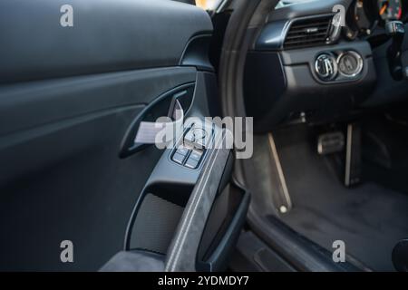 Luxury car door panel featuring window switches, fabric strap, and soft-touch materials. Stock Photo