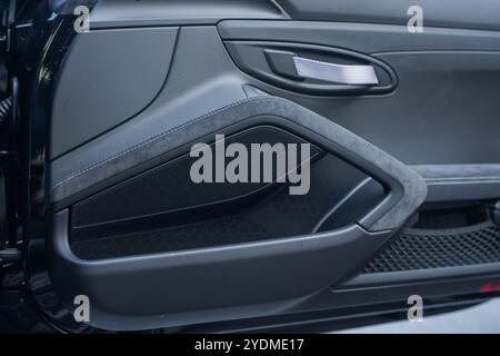 Luxury car door interior with fabric pull handle and window controls. Stock Photo