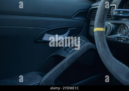 Luxury car door interior with fabric pull handle and window controls. Stock Photo