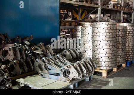 A factory storage area filled with stacks of industrial metal parts and components, ready for use in manufacturing or assembly. Stock Photo