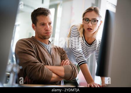 Upset businesspeople trying to work on line with a desktop computer looking at monitor at office Stock Photo