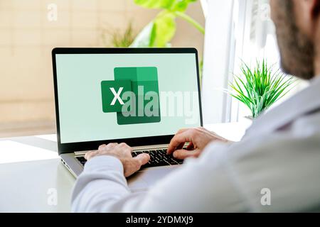 Man using a laptop computer displaying logo of Microsoft Excel on the screen. Spreadsheet software for calculate, formulas and productivity. ROSARIO, Stock Photo